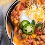 Taco soup with cheese and Jalapenos on top.